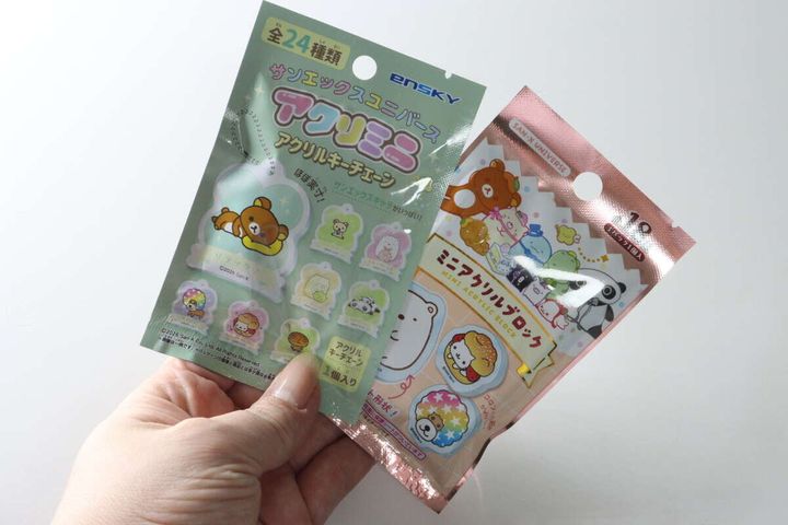 女性がサンエックスのアクリルキーチェーンとアクリルブロックのパッケージを両手に持っている