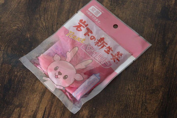 ピンク色のパッケージに入った岩下の新生姜スライスnextが木目のテーブルに置かれている