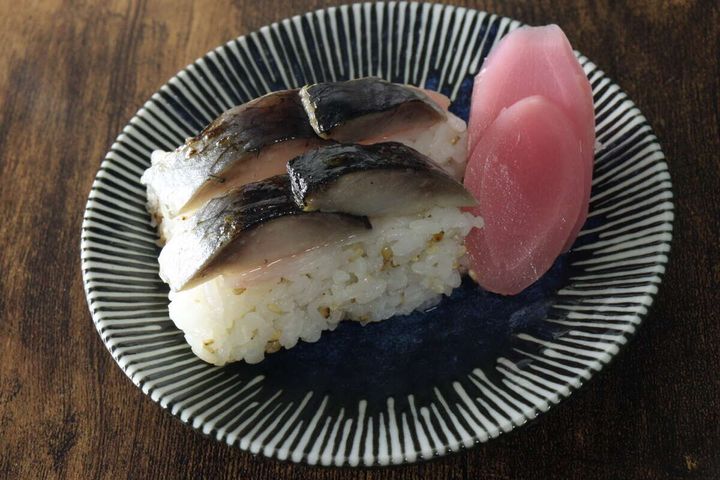 縞模様の皿に盛り付けられた鯖の押し寿司と、付け合わせのピンク色の新生姜スライス