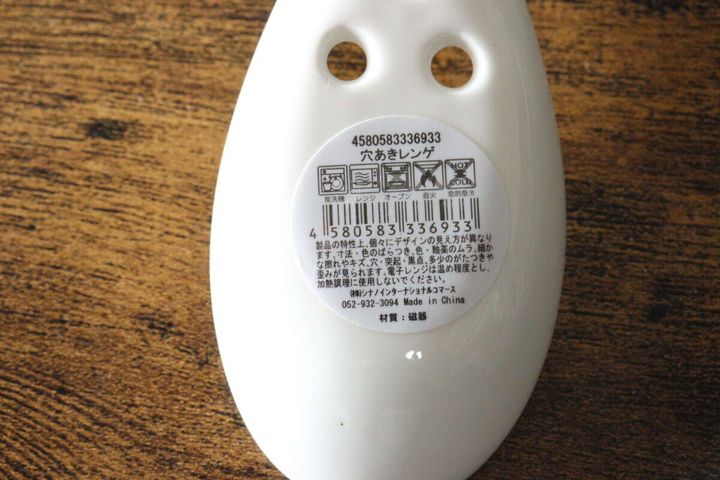 白い陶器製穴あきレンゲの裏側に貼られた商品情報とJANコードのシール