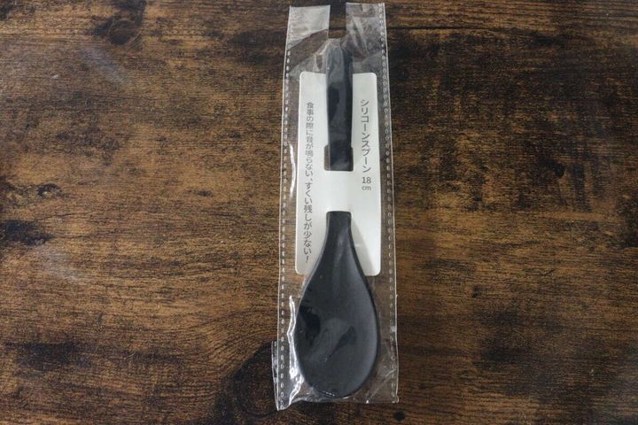 黒いシリコーンスプーンが透明なパッケージに入った状態で木目のテーブルに置かれている