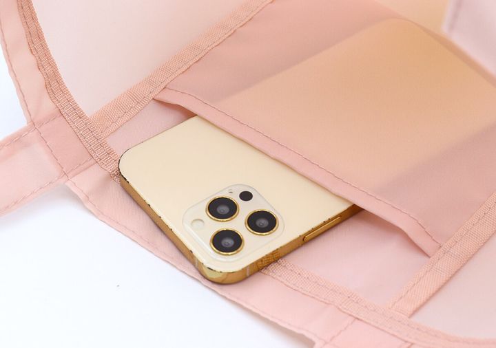 ピンクのトートバッグの内ポケットにスマホを入れている様子