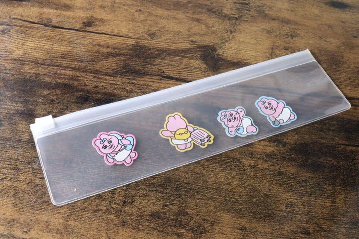 細長いクリアポーチに、クマのイラストの缶バッジが3つ並んで収納されている