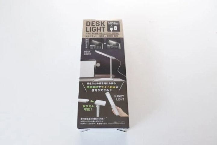 白い箱に入った「DESK LIGHT -USB/乾電池 両用-」のパッケージ。デスクライトと手持ちライトのイラスト。