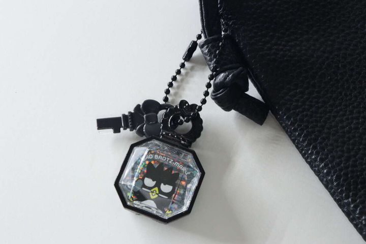 バッドばつ丸のジュエルキーホルダーが黒いバッグの持ち手に付けられている