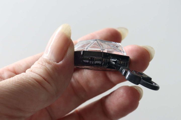 女性の指でジュエルキーホルダーのフタが鍵で開けられている様子