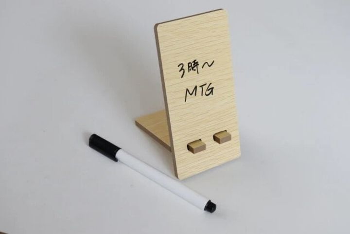 木目調ホワイトボードに「3時〜MTG」と書かれマーカーが置かれている