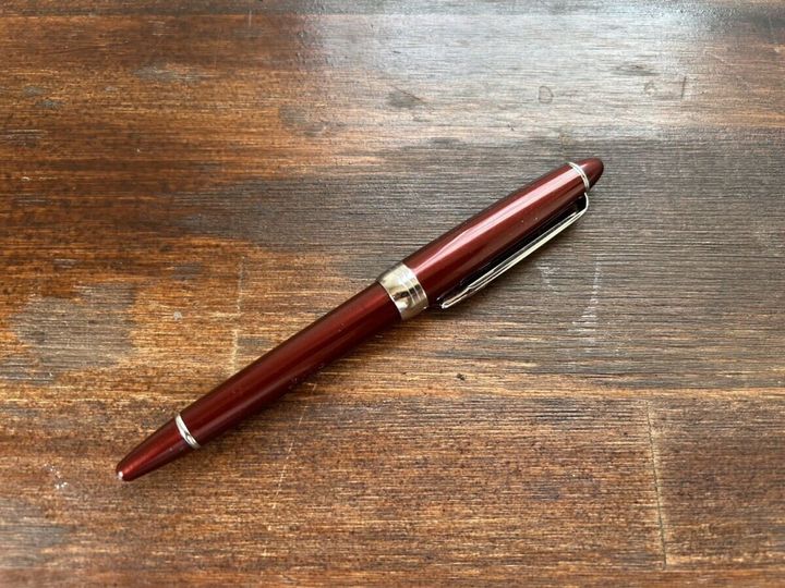木目調のテーブルに置かれた赤茶色の光沢がある万年筆