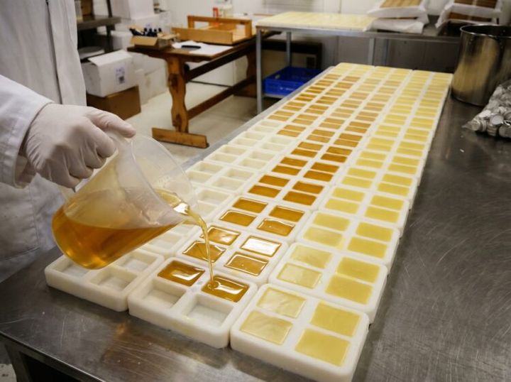 工房で、型に流し込まれた黄色い石けんの液を確認する作業の様子