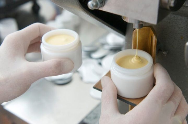 白い容器にクリームを充填する手元