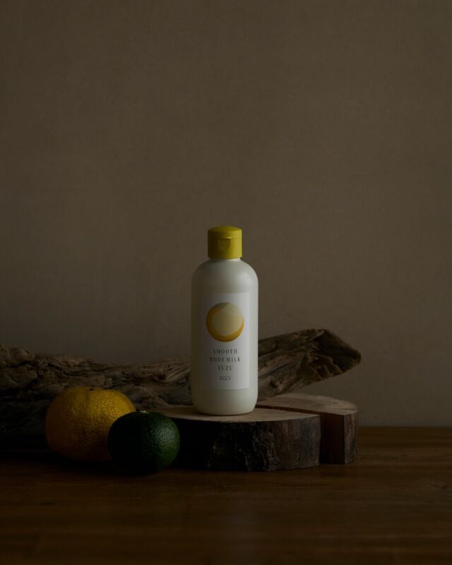 ゆずと流木のそばに置かれた、OSAJIのYuzu〈ユズ〉シリーズのボトル