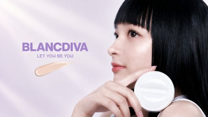 淡いピンクの背景でBLANCDIVAのクッションファンデーションを手にする黒髪の女性