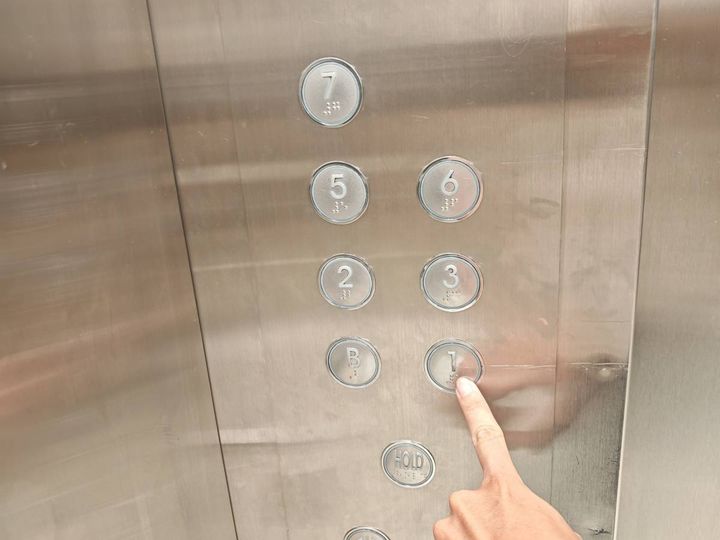 エレベーターを押す人の手元