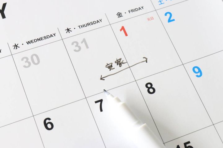 ダイソーのホワイトボードカレンダーに「実家」と予定が書き込まれている様子。