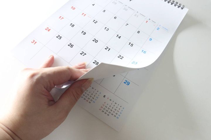 女性の指がダイソーのホワイトボードカレンダーのページをめくっている。