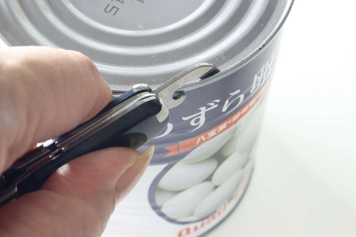 マルチツールの缶切りで缶詰の蓋を開けようとしている様子