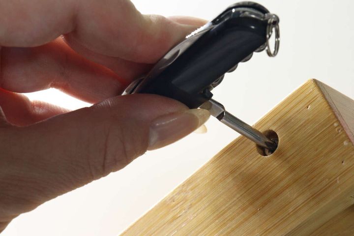 マルチツールのプラスドライバーで木材のネジを回している様子
