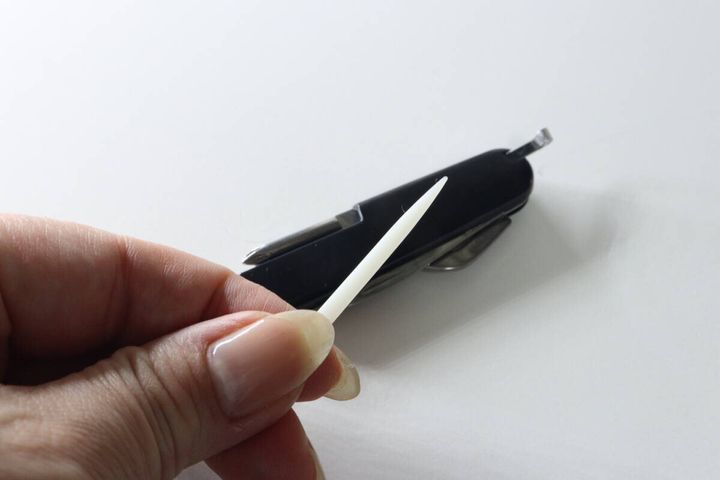 マルチツール本体からプラスチック製のピックを引き出している指先
