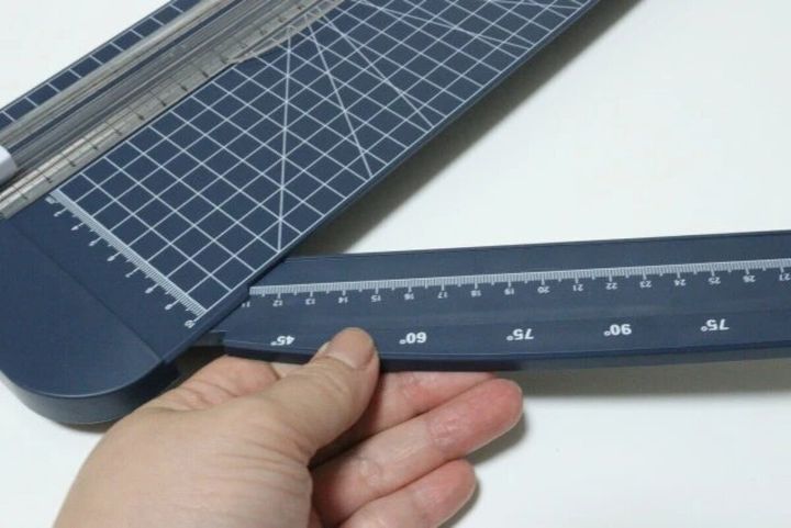 ペーパーカッターの側面から、目盛りが付いた延長バーを左手で引き出している