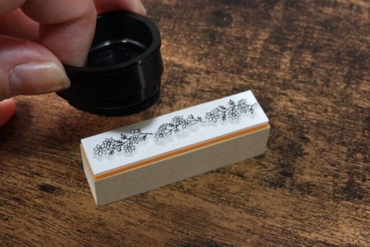 ボタニカル柄のスタンプに黒いインクパッドを押し当ててインクを付けている