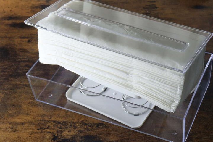 透明なティッシュケースの底にスプリングホルダーをセットし、その上にティッシュを置いている工程