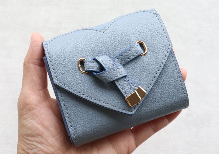 女性の手のひらに乗せられたサックスブルーのハートカットミニ財布