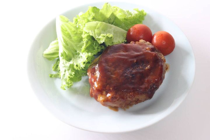 完成したハンバーグにサラダとミニトマトが添えられた皿