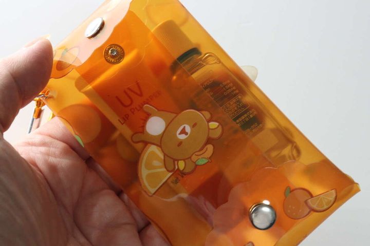 リラックマ柄クリアポーチに目薬とリップを入れている手元