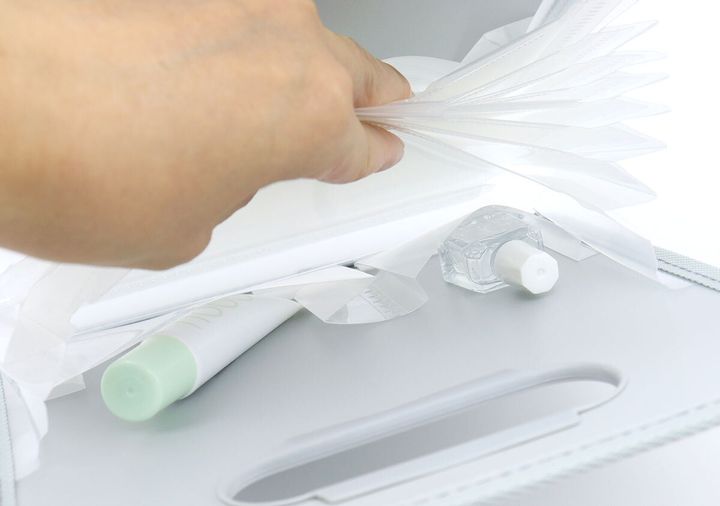 グレーのコクヨお薬ファイルの内ポケットに軟膏と消毒液を収納している手元