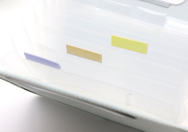 グレーのコクヨお薬ファイルのじゃばらポケットに貼られたカラフルなインデックスのアップ