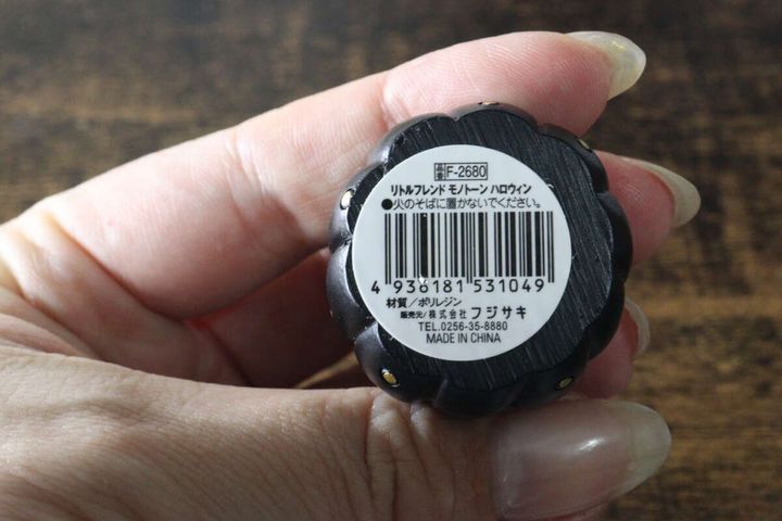 手に持った黒いかぼちゃ型オブジェの底面にある商品ラベル