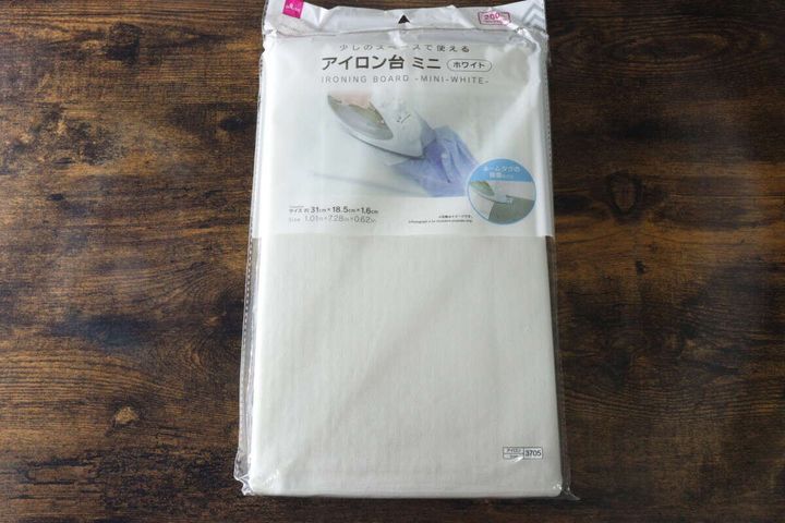 ダイソーのミニアイロン台（ホワイト）のパッケージが木製テーブルに置かれている