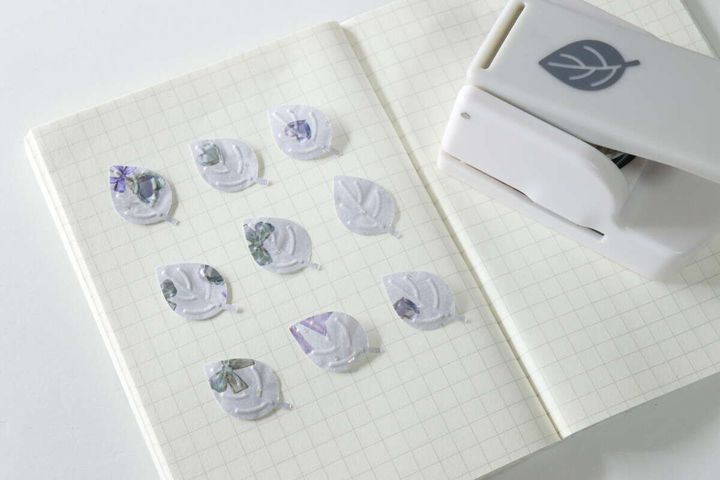 ノートの上にクラフトパンチとエンボス加工された葉っぱ型の紙片が並べられている