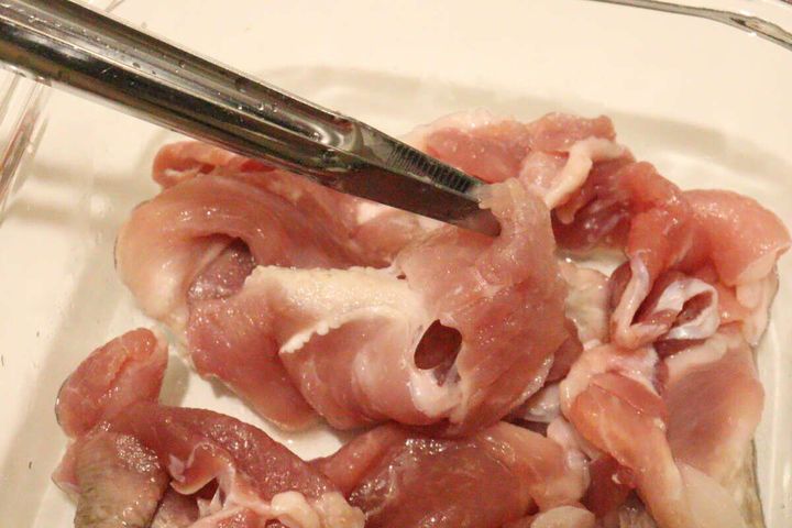 透明な容器に入った鶏肉をステンレス製の「箸トング」で掴んでいる様子
