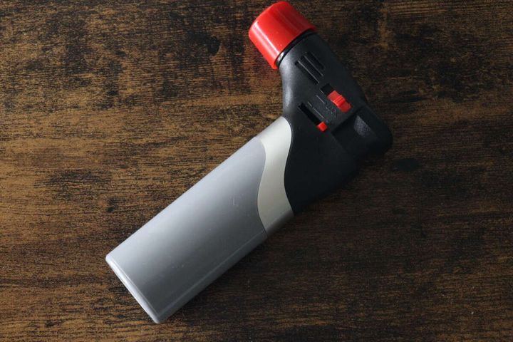 ダイソーのコンパクトガスバーナー本体が木目調のテーブルに置かれている