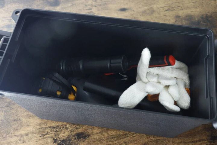黒い防滴工具箱の蓋が開いており、中に懐中電灯や白い軍手などの工具が入っている様子
