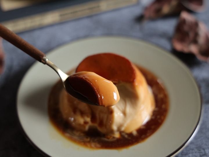 皿に盛り付けられたプリンを、カラメルソースと一緒にスプーンですくっている。