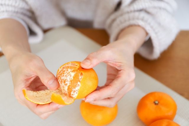 みかんの皮を剥く人の手