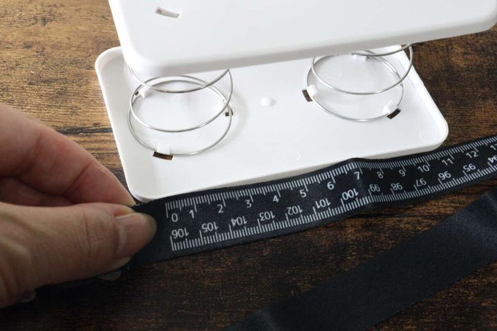 ストラップのメジャーで白いケースを測る手