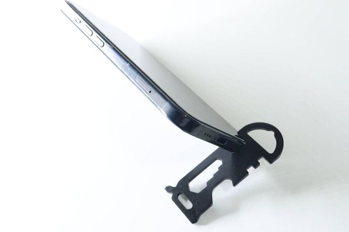 黒いマルチツールをスタンドにしてスマートフォンが立てられている