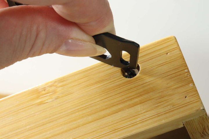 女性の指がマルチツールのドライバーで木箱のネジを回している