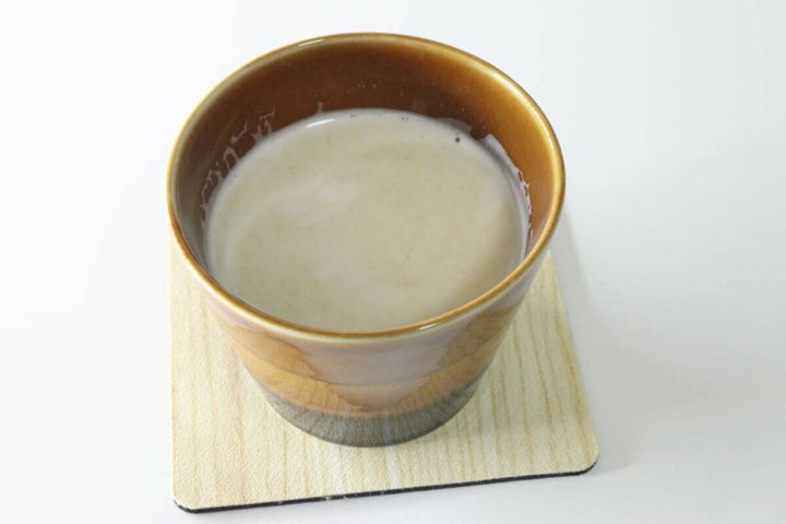 木製コースターに乗った、完成したジンジャーラテが入った茶色のカップ