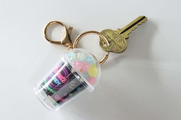お菓子カップ型キーホルダーのリングにゴールドの鍵が装着されている