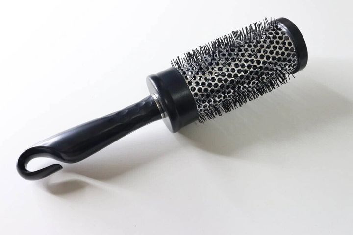 黒い持ち手と金属製の筒状のブラシ部分を持つロールヘアブラシ