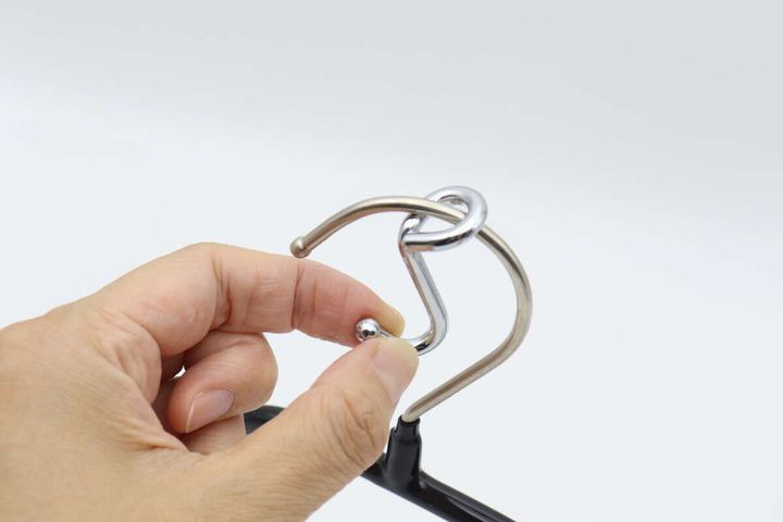 手がハンガー連結用フックをハンガーのフック部分に通している途中