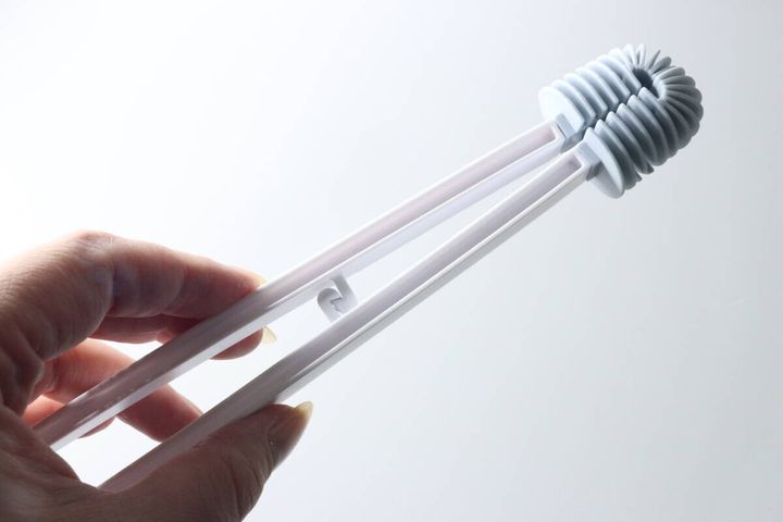 女性の手がダイソーの『洗ってポイ トイレ用クリーナートング』を握っている様子