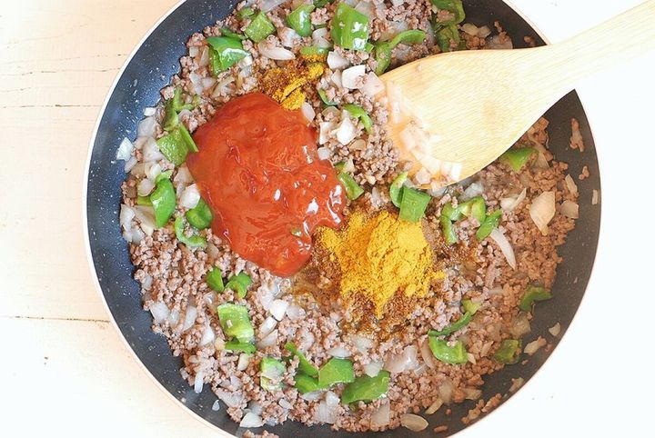 炒めているひき肉と野菜の上にカレー粉とケチャップが加えられた調理中の俯瞰写真