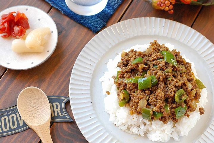 完成したピーマンドライカレーがご飯に盛られ、福神漬けとらっきょうが添えられた食卓の斜めからの写真