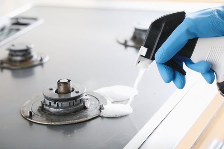【1】五徳などの付属品を外す。ゴム手袋をつけ、油汚れ用洗剤をコンロの天板全体にスプレーする。5分ほど置き、飛び散った油や調味料などの汚れなどを緩ませる。