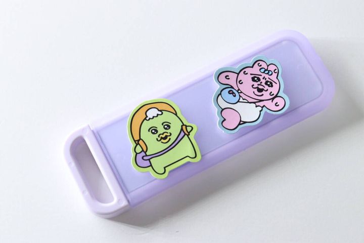 紫色のミラーの裏面に緑とピンクのキャラクターシールが貼られデコレーションされている